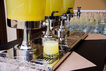 Three beverage dispensers with lemonade standing on the table. Refreshment drinks. Self serving...