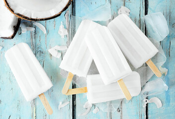 Coconut popsicles in a cluster. Top view table scene over a blue wood background.