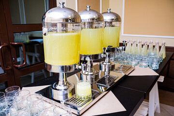 Three beverage dispensers with lemonade standing on the table. Refreshment drinks. Self serving...