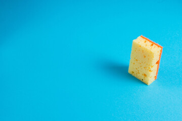 Yellow porous sponge for cleaning on a blue background with copy space. Home cleaning concept