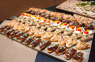 Bruschetta with different kinds of spreads. A set of appetizers on a wooden board. Catering serving.