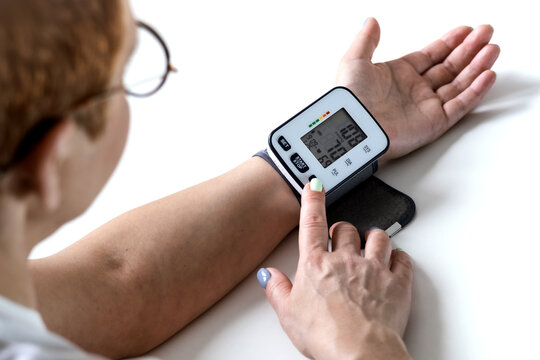 A woman checks her blood pressure, a tonometer is worn on her wrist