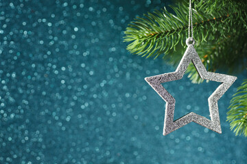 silver star on a Christmas tree branch on a blue shining bokeh background, new year decorations.