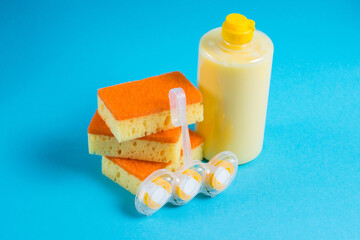 Sponges for cleaning and washing dishes, toilet block and detergent in a transparent plastic bottle on a blue background. Home cleaning concept