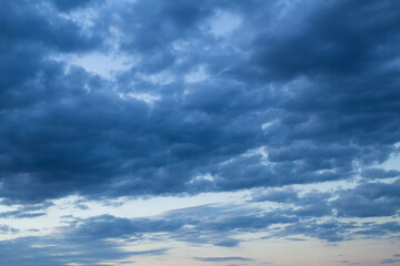 Naklejka na ściany i meble Natural background. Blue sky with clouds at sunset. Closeup.