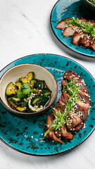 Japanese cuisine. Meat dish with vegetables on a white table.
