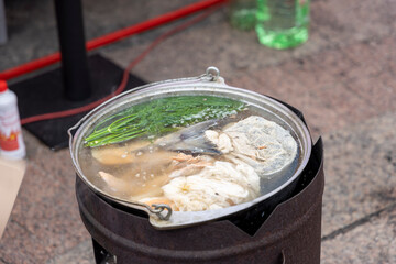 A cauldron in which fish soup is cooked with different ingredients
