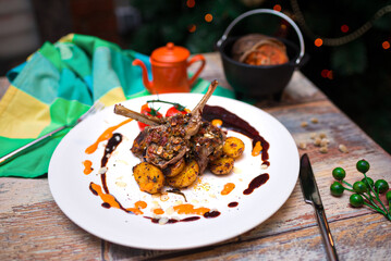 rack of lamb with baked mini potatoes on a plate covered in drops of souse