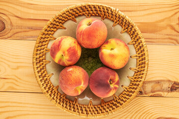 Naklejka na ściany i meble Several juicy ripe peaches with a ceramic plate on a wooden table, close-up, top view.