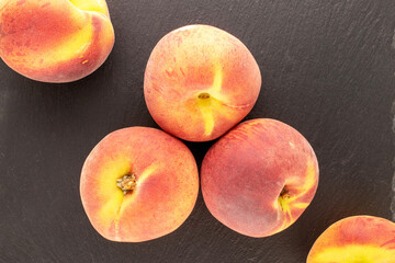 Several juicy ripe peaches on a slate stone, close-up, top view.
