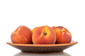 Several sweet organic peaches on a ceramic plate, close-up, isolated on a white background.