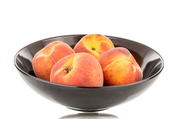 Several sweet organic peaches with a black ceramic plate, close-up, isolated on a white background.