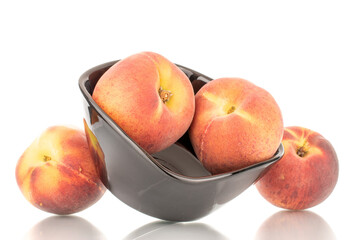Several sweet organic peaches with a black ceramic plate, close-up, isolated on a white background.