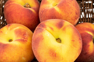 Several sweet organic peaches in a basket, close-up.