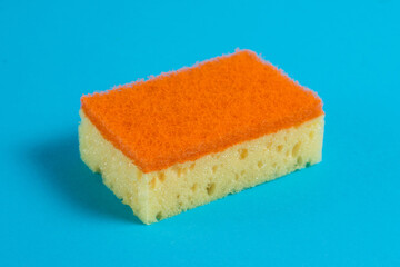 Porous sponge for washing dishes and cleaning in the apartment on a blue background. The concept of using environmentally friendly detergents for the home