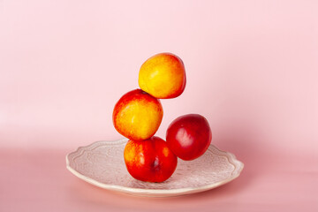 the balance of nectarines on a white antique porcelain plate on a pink background