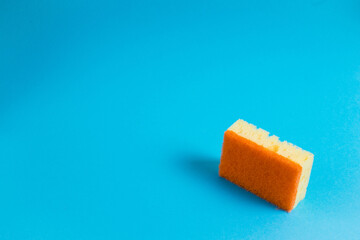 Yellow porous sponge for cleaning on a blue background with copy space. Home cleaning concept