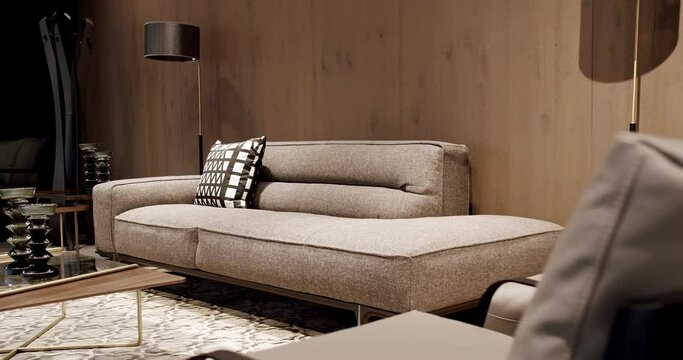 Modern gray and beige fabric sofa. Modern apartment beautiful beige sofa in modern living room with lamp and carpet, table. Scandinavian interior with wooden wall. Textile upholstery sofa with pillows