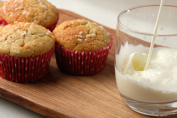 homemade breakfast or snack, three delicious and fluffy muffins with a glass of milk, on a rustic wooden plate.