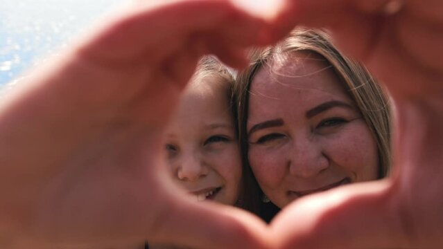 Mother and daughter showing a heart of their fingers to the camera