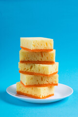 Sponges for washing dishes and cleaning in the apartment on a plate on a blue background. The concept of using ecological detergents for the home