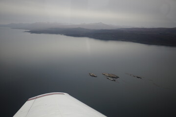 the photo captures the moment of takeoff and flight by plane over Ushuaia — a city and port in...