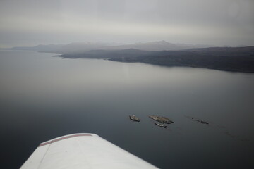 the photo captures the moment of takeoff and flight by plane over Ushuaia — a city and port in...