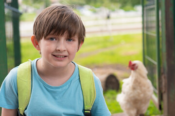 portrait of a boy with a rooster on the farm
