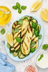 Grilled zucchini slices in a blue plate on a marble  background. Healthy summer veggie food. Top view