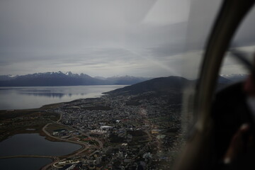 the photo captures the moment of takeoff and flight by plane over Ushuaia — a city and port in...