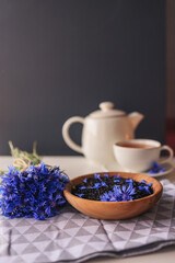 Black natural tea with cornflower petals on the table