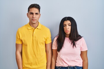 Fototapeta premium Young couple standing over isolated background depressed and worry for distress, crying angry and afraid. sad expression.