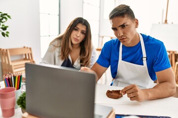 Obraz premium Two students with serious expression having artistic online class using laptop at art school.