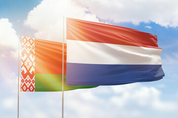 Sunny blue sky and flags of netherlands and belarus