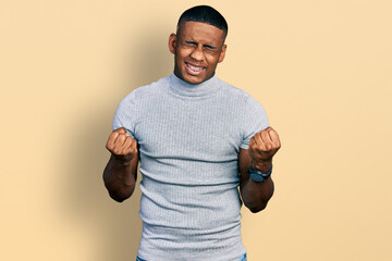 Young black man wearing casual t shirt very happy and excited doing winner gesture with arms...