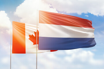 Sunny blue sky and flags of netherlands and canada