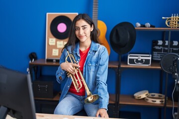 Young hispanic girl musician holding trumpet at music studio © Krakenimages.com
