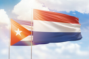 Sunny blue sky and flags of netherlands and cuba