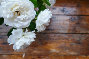 White roses on a wooden background. Place for text. Holiday postcard. Copy space
