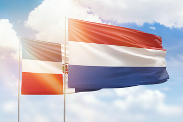 Sunny blue sky and flags of netherlands and dominican republic