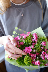 Bouquet of pink beautiful roses in the hands of a woman. Stylish flowers in the hands of a florist. The girl collected a fresh bouquet in pink and green shades. Beautiful delicate flowers