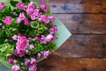 Bouquet of pink-green flowers on a wooden background. Roses top view. Place for text. Holiday postcard. Copy space
