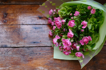 Bouquet of pink-green flowers on a wooden background. Roses top view. Place for text. Holiday postcard. Copy space