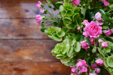 Bouquet of pink-green flowers on a wooden background. Roses top view. Place for text. Holiday postcard. Copy space