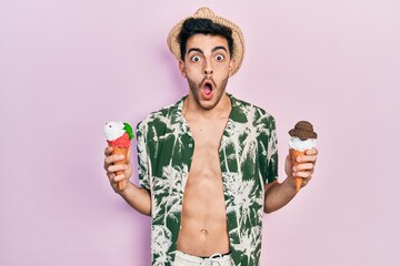 Young hispanic man wearing summer style holding ice cream afraid and shocked with surprise and amazed expression, fear and excited face.