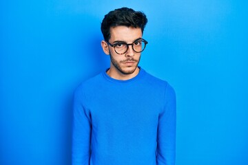 Young hispanic man wearing casual clothes and glasses skeptic and nervous, frowning upset because...
