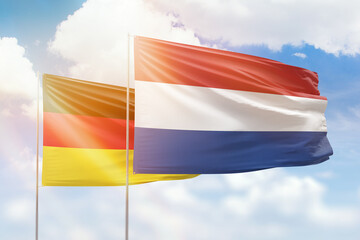 Sunny blue sky and flags of netherlands and germany