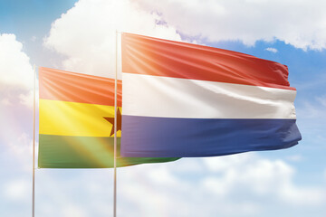 Sunny blue sky and flags of netherlands and ghana