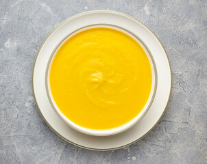 Top view vegan pumpkin soup in the white bowl on concrete surface