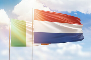 Sunny blue sky and flags of netherlands and ireland